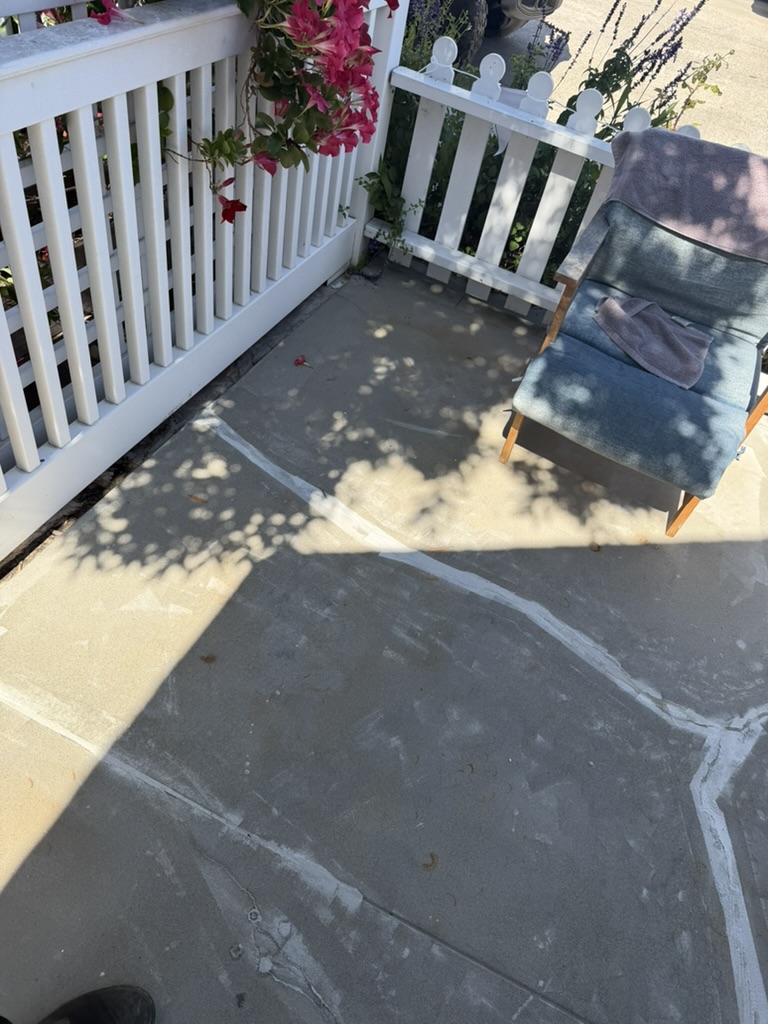 Patio crack traced and marked near railing before repair