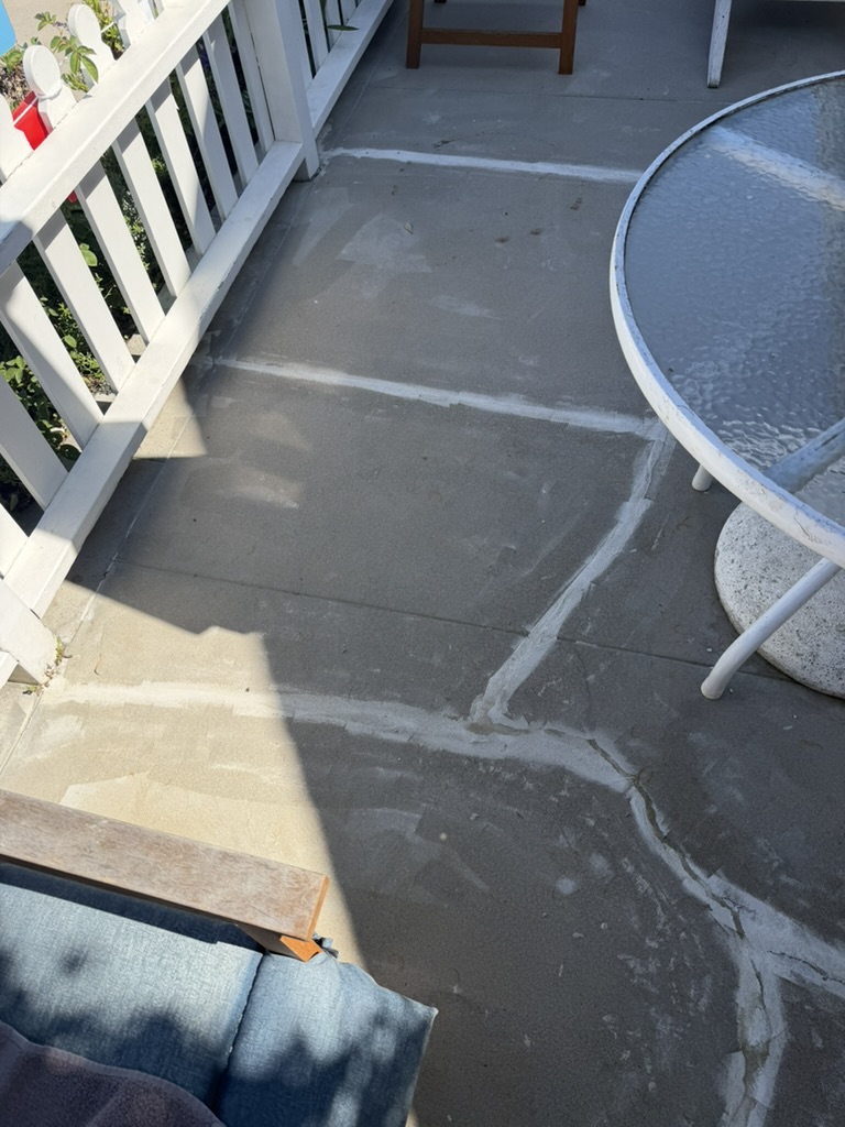 Cracked concrete patio marked out near patio table before grinding